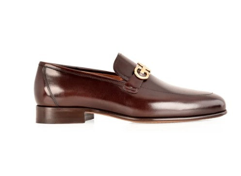 A dark brown leather loafer with a silver-tone hardware on the vamp, shown in a side profile against a white background.