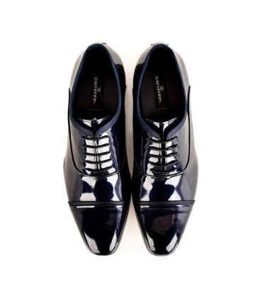A pair of glossy black patent leather oxford shoes with cap toes and laces, photographed from a top-down perspective on a white background.
