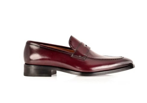 A single dark burgundy leather penny loafer with a polished finish and a low black stacked heel, shown in profile against a white background.