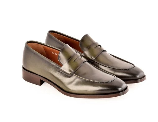 A pair of metallic green leather penny loafers with brown soles, displayed on a clean white background.