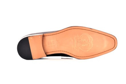 Top-down view of a men's dress shoe sole, showing a tan leather insole with an embossed logo, a black heel cap, and a white midsole band on a white background.