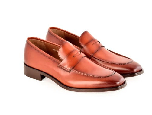 A pair of men's penny loafers in smooth tan leather, shown from a three-quarters angle on a clean white background.