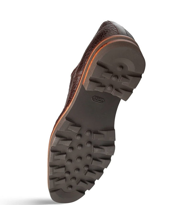 A single brown textured leather shoe shown from the sole side, featuring a dark gray lug outsole and a thin orange-brown edge detail.