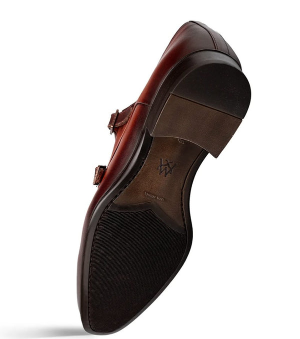 A single men's leather loafer shown from a high-angle underside view, featuring a dark brown leather upper with a double strap buckle closure and a textured brown outsole.