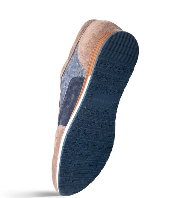 A single casual slip-on shoe shown from a side angle, featuring a navy blue textured sole, a navy blue side panel, a tan suede heel, and a blue denim-like side section on a white background.