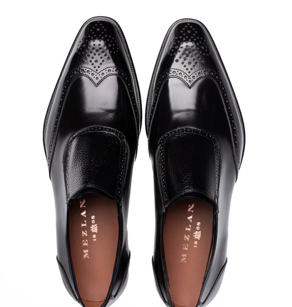 A pair of black leather men's dress shoes with brogue detailing, shown from a top-down view on a white background. The brand name 'MEZLAN' is visible on the tan insoles.