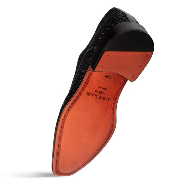 A single men's dress shoe shown from the sole side, featuring a black textured leather upper and a contrasting orange-red rubber outsole, photographed on a white background.
