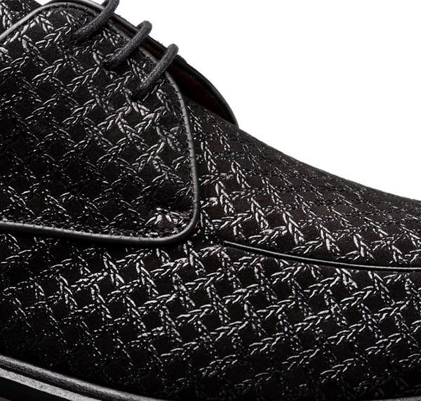 Close-up of a black leather lace-up shoe with a textured geometric pattern and black laces, shown against a white background.