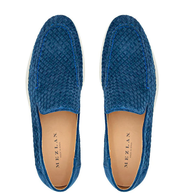 A pair of blue woven slip-on loafers with a tan insole, shown from a top-down view on a white background. The brand name 'MEZLAN' is printed on the insole.