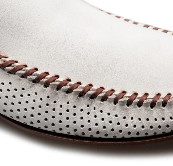 Close-up of a white leather moccasin shoe with brown contrast stitching and perforated detailing.