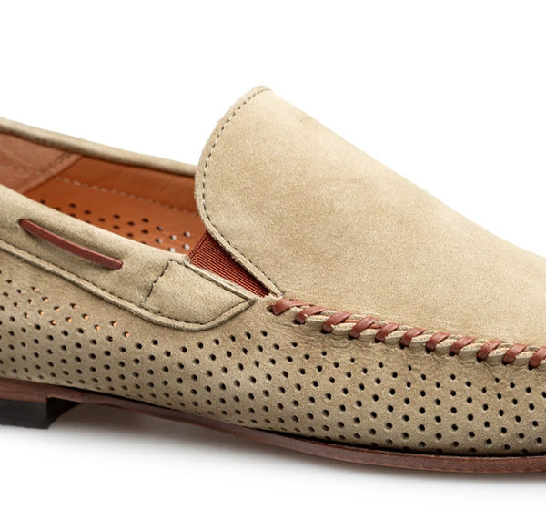 A close-up of a beige suede loafer with perforated detailing, brown stitching, and a brown leather interior, shown on a white background.