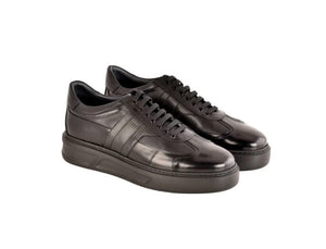 A pair of black leather low-top sneakers with black laces and thick black platform soles, shown on a plain white background.