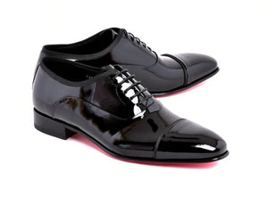 A pair of glossy black patent leather cap-toe oxford shoes with black laces, displayed on a clean white background.