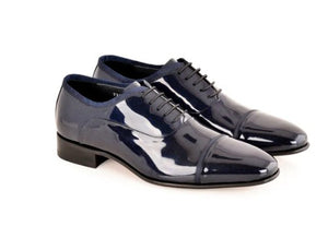 A pair of navy blue patent leather oxford shoes with black laces, displayed on a clean white background.