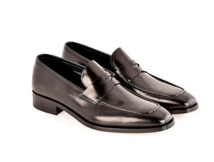 A pair of black leather penny loafers with low block heels, displayed on a clean white background.