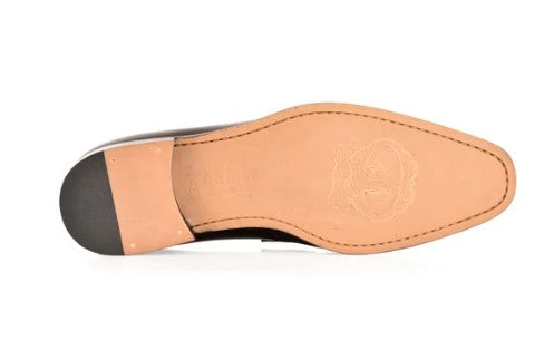 The underside of a men's dress shoe showing a tan leather insole, a black rubber heel cap, and a light tan heel block, photographed on a white background.