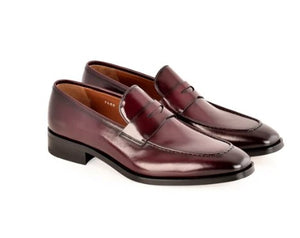A pair of glossy dark burgundy leather penny loafers with a low stacked heel, displayed on a clean white background.