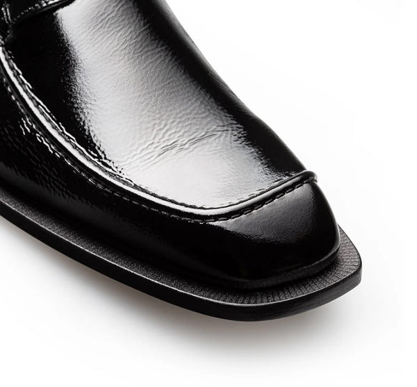Close-up of a black leather loafer shoe showing the toe cap, side stitching, and textured sole on a white background.