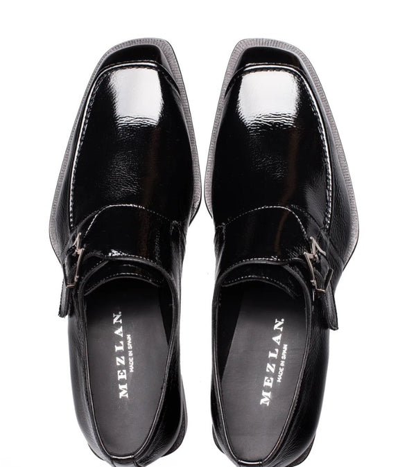 A pair of black leather loafers with square toes and double strap buckles, shown from a top-down view on a white background. The brand name 'MEZLAN' is printed in white on the insoles.