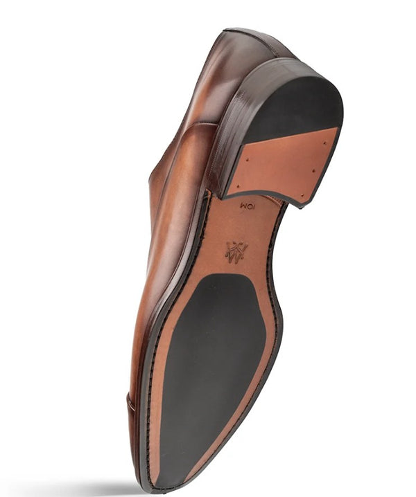 A single men's dress shoe shown from the sole side, featuring a polished medium brown leather upper, a black rubber outsole, and a tan leather insole with a logo.