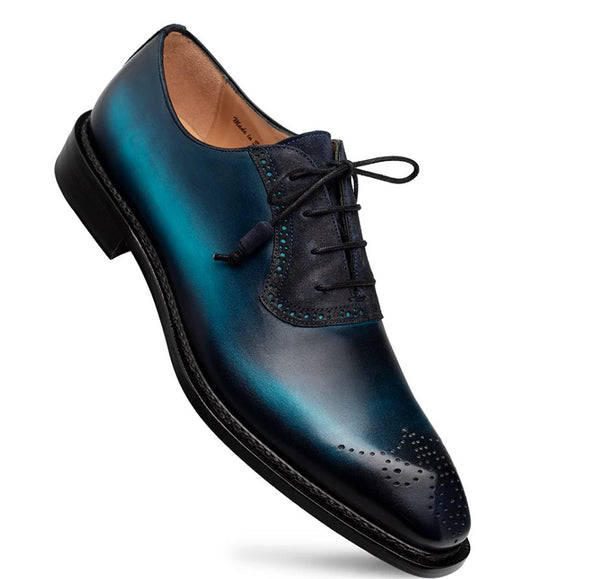 A men's oxford dress shoe with a metallic teal and navy blue gradient finish, featuring brogue detailing on the toe and a black sole.