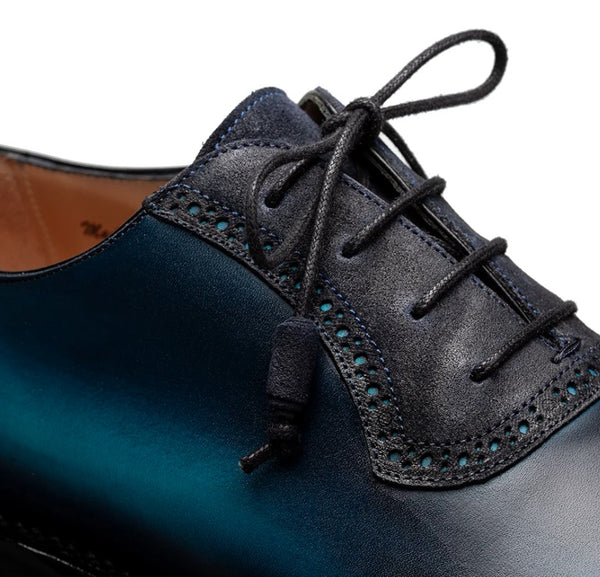 Close-up of a men's dress shoe showing the side panel, lace area, and toe cap on a white background.
