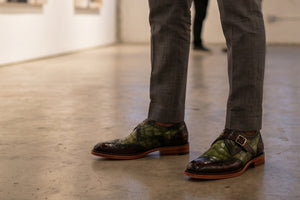Man standing with Green and burgundy shoes with a buckle on them.