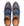 A pair of low-top slip-on sneakers shown from a top-down view on a white background. The shoes feature a textured blue denim-like upper, brown suede overlays, and bright blue elastic laces.