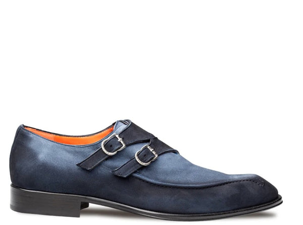 A navy blue suede double strap monk shoe with silver buckles and a black sole, shown from a side profile on a white background.