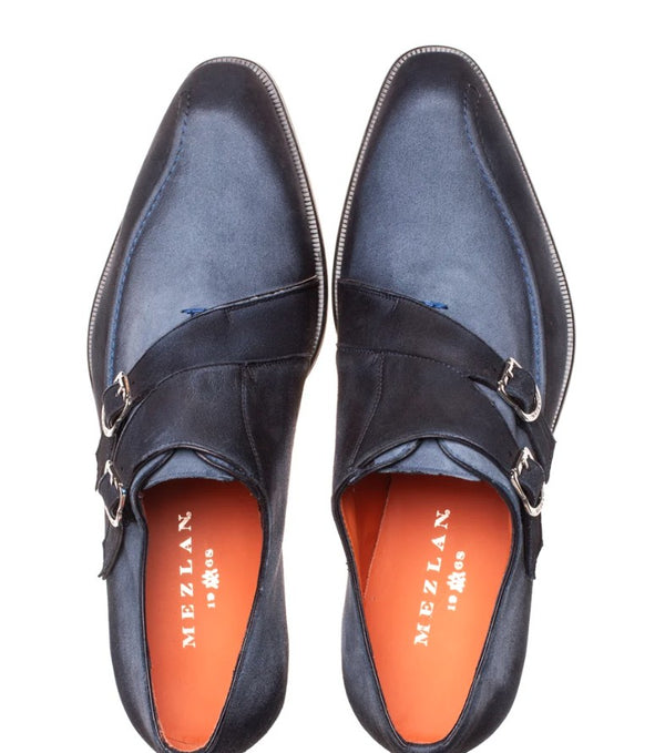 A pair of dark navy blue leather monk strap shoes with silver buckle details and bright orange insoles, shown from a top-down view on a white background.