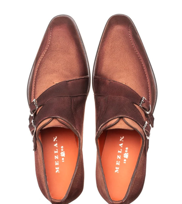 A pair of brown leather double-strap loafers with silver buckle details, shown from a top-down view on a white background. The brand name 'MEZLAN' is visible on the orange insoles.