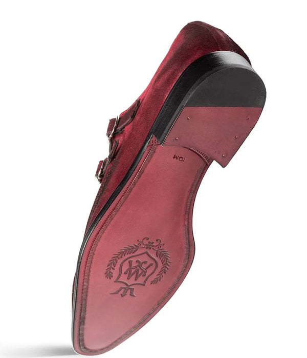A single men's dress shoe shown from the sole side, featuring a burgundy suede upper, black leather trim, and a matching burgundy sole with an embossed monogram logo.