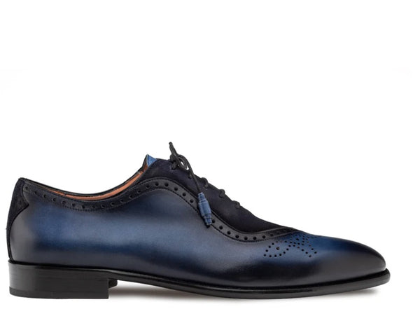 A single men's wingtip oxford shoe in dark navy blue leather, shown from a side profile against a plain white background.