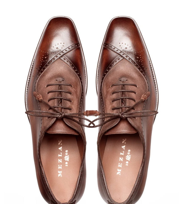 A pair of brown leather oxford shoes with decorative brogue perforations and matching laces, shown from a top-down view on a white background. The insoles display the brand name 'MEZLAN'.