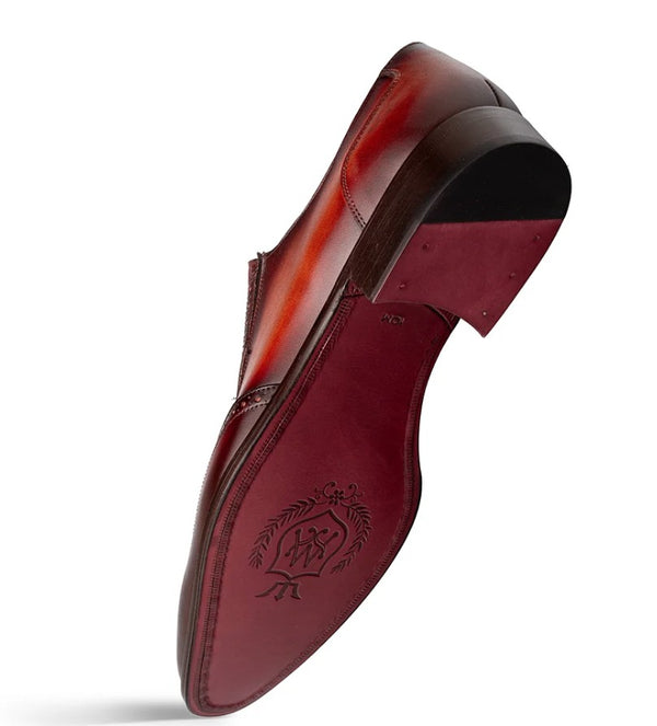 A single men's dress shoe shown from the sole side, featuring a glossy dark red-brown leather upper and a matching red-brown outsole with an embossed logo, photographed on a white background.