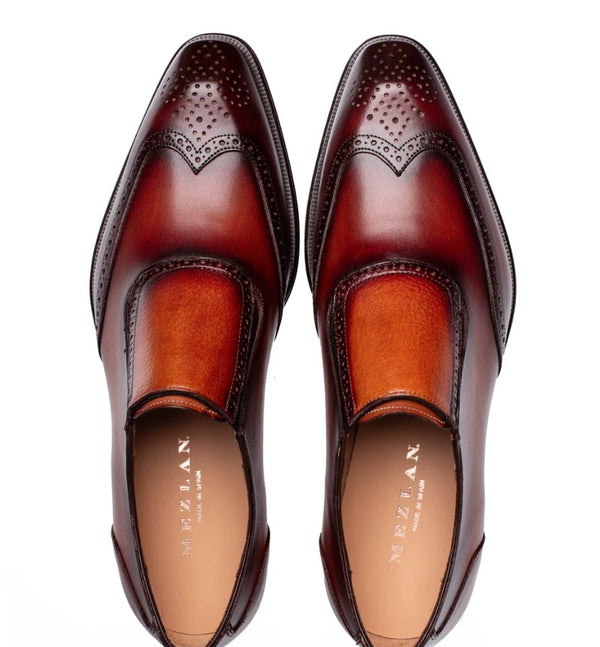A pair of men's wingtip loafers in a rich two-tone brown leather photographed from a top-down angle on a white background.